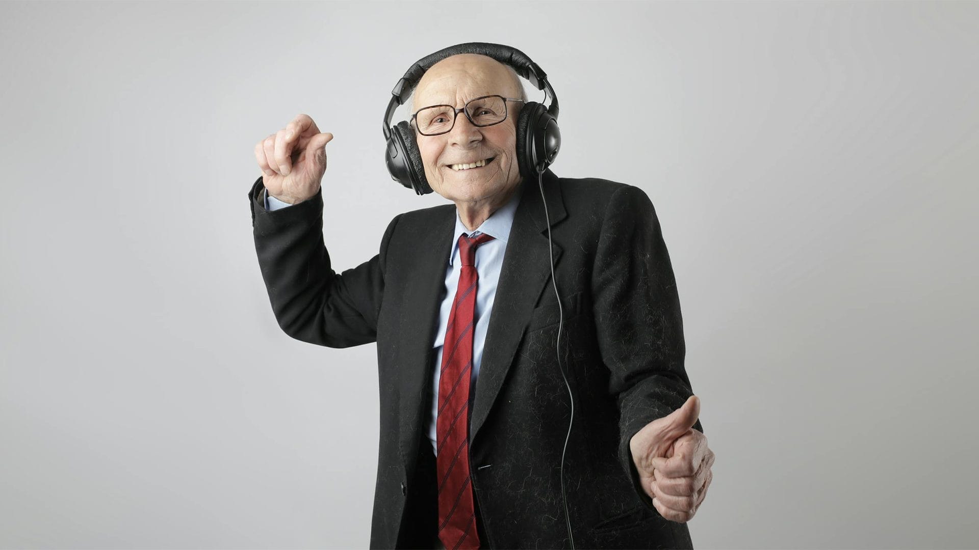 A senior with dementia or Alzheimer's joyfully dances while wearing headphones, immersed in the therapeutic experience of music therapy.