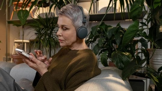 A woman with Alzheimer's disease listens to music through headphones, experiencing the therapeutic benefits of sensory stimulation.